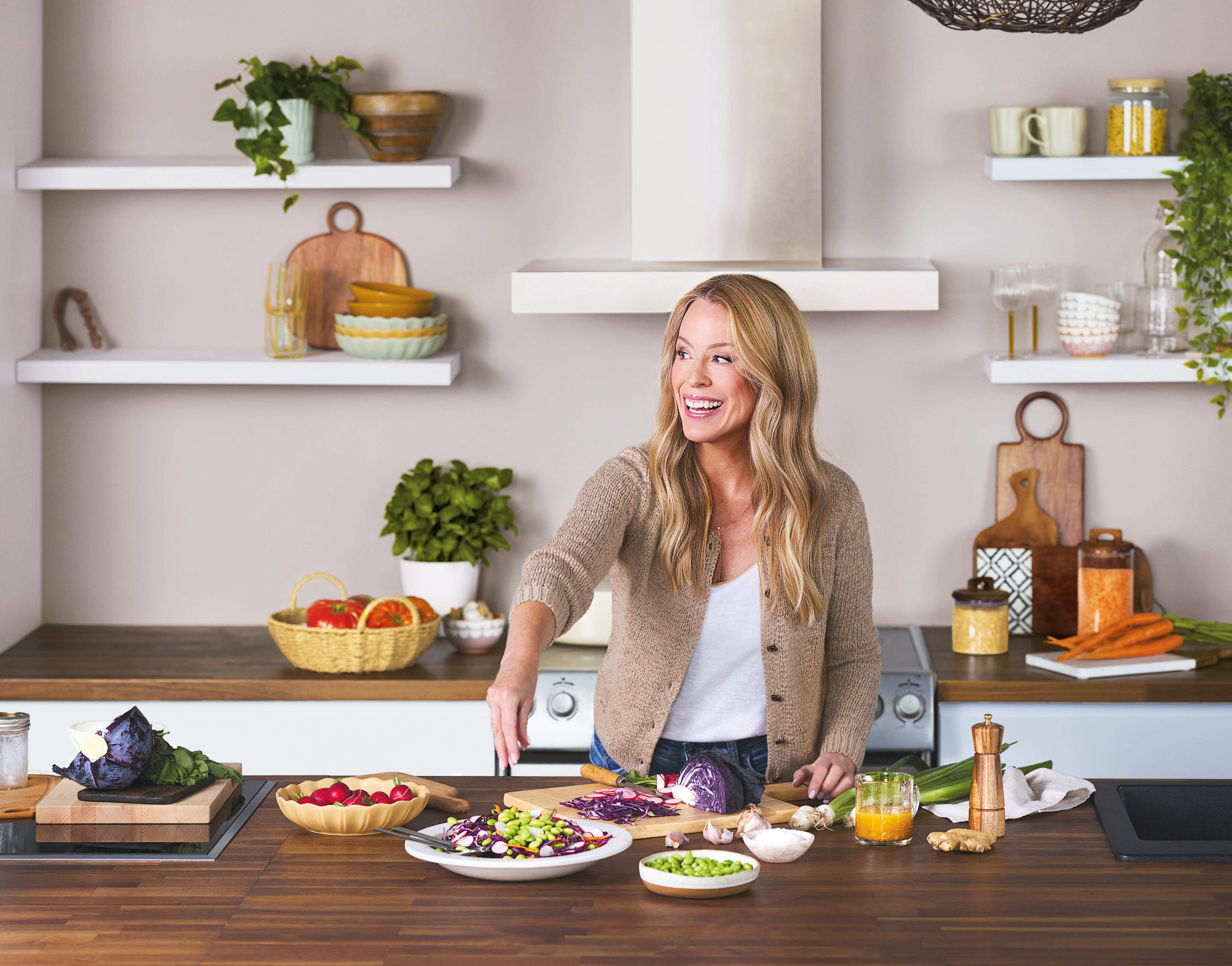 Isabelle Huot préparant une recette colorée avec des légumes frais dans une cuisine moderne et lumineuse.
Isabelle Huot preparing a colorful recipe with fresh vegetables in a modern, bright kitchen.